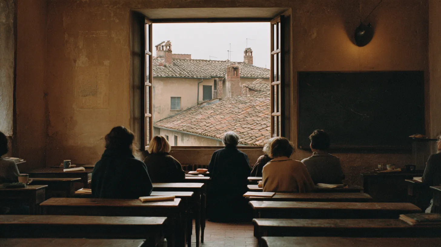 Adult students seen from behind at wooden desks in a high-ceilinged classroom, a tall open window looking onto terracotta rooftops, afternoon light